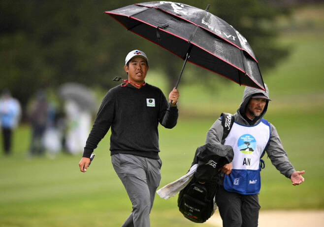 안병훈이 5일 AT&T 페블비치 프로암 3라운드가 중단되자 우산을 쓰고 이동하고 있다.(사진=AFPBBNews)