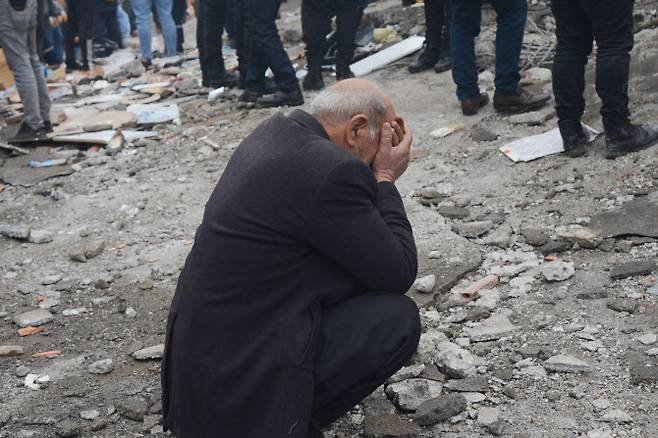 무너진 잔해 속에서 한 남성이 생존자를 찾고 있다. (사진=AFP)