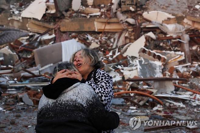 강진 발생 다음날인 7일(현지시간) 지진으로 붕괴한 튀르키예 하타이의 건물 잔해 앞에서 두 사람이 서로 끌어안고 있다. /사진=연합뉴스