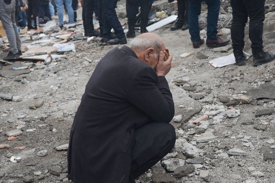 한 남성이 튀르키예의 무너진 건물에서 생존자들을 찾고 있는 사이 얼굴을 감싸 쥐고 주저앉았다. AFP=연합뉴스