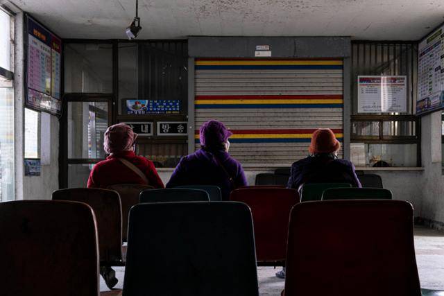 털모자를 쓴 지역 주민들이 14일 전북 김제시 원평공용버스터미널에서 버스를 기다리고 있다. 굳게 닫힌 매표소 셔터와 전등 하나 켜지지 않은 터미널의 황폐한 모습은 소멸하는 지방의 모습과 일맥상통한다. 지역이 쇠퇴해 교통도 쇠퇴하고, 교통이 쇠퇴해 지역이 쇠퇴하는 악순환인 것이다.