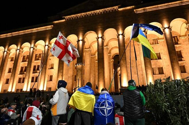 7일(현지시간) 조지아 트빌리시 국회의사당 앞에서 시위대가 조지아, 우크라이나, 북대서양조약기구(나토) 깃발을 흔들며 경찰과 대치하고 있다. AFP연합뉴스