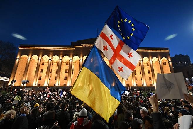 8일(현지시간) 조지아 트빌리시 국회의사당 앞에서 외국 대리인법에 반대하는 시위대가 조지아, 우크라이나, 유럽연합 깃발을 흔들고 있다. AFP연합뉴스