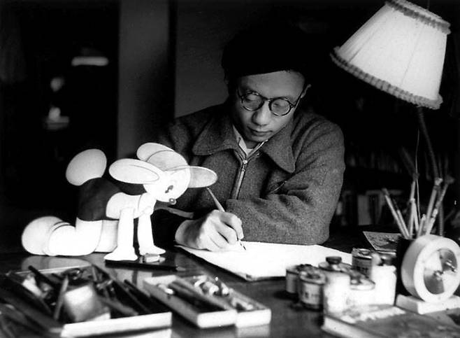 20대 시절 데즈카 오사무 감독의 작업 모습. 만화 <로스트월드> 캐릭터 ‘미미오’가 그를 지켜보듯 책상 위에 앉아 있다. 데즈카 오사무 공식 누리집