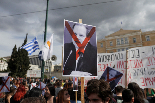 그리스 아테네 의회 앞에서 지난 12일 시위대가 코스타스 카라만리스 전 교통장관 얼굴에 엑스(X)를 표시한 사진을 들어올리며 정권 퇴진 구호를 외치고 있다. 로이터 연합뉴스