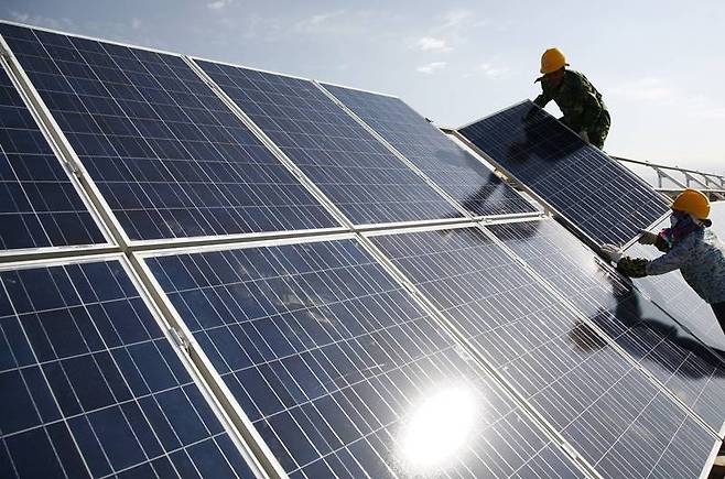 중국 신장위구르 자치구의 한 태양광발전소에서 노동자들이 태양광 패널을 설치하고 있다. [AP=연합]