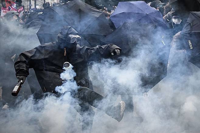 프랑스 연금개혁 반대 시위대가 23일(현지시각) 프랑스 낭트에서 시위대를 향해 날아든 최루탄을 발로 차 내고 있다. 낭트/AFP 연합뉴스