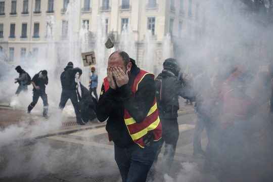 23일(현지시간) 프랑스 리옹에서 연금개혁 반대 시위 참가자들이 체루탄 연기를 피해 달아나고 있다. AP·연합뉴스