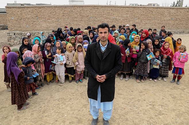 대학생인 교사인 와지르 칸과 어린이들이 29일 아프가니스탄 카불 야외 학교 교실에서 수업을 마친 뒤 사진을 찍기 위해 함께 모여 있다. 카불/EPA 연합뉴스