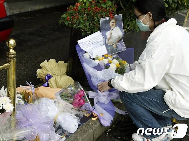 가수이자 배우인 장국영이 사망한 다음날인 2003년 4월2일, 한 팬이 센트럴 비즈니스 지구의 만다린 호텔 밖에 꽃과 메시지를 놓고 있다.ⓒ AFP=뉴스1