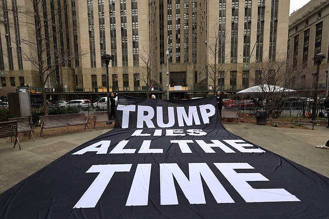 23일(현지시간) 미국 뉴욕 맨해튼법원 인근 공원에 ‘트럼프는 항상 거짓말을 한다’라는 문구가 적힌 대형 펼침막이 설치돼 있다.  [사진 = 뉴욕 로이터 연합뉴스]