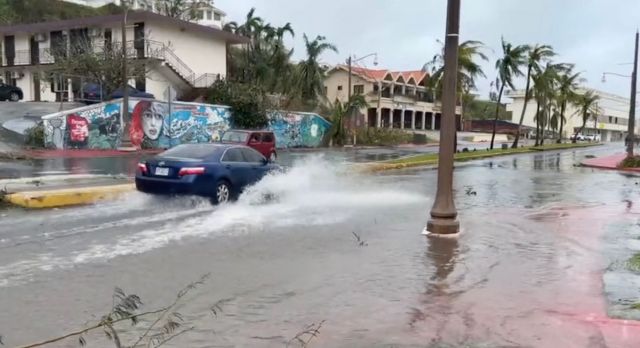 시속 241㎞의 돌풍을 동반한 '슈퍼 태풍' 마와르가 태평양의 미국령 괌을 강타한 25일(현지시간) 한 자동차가 투몬 만의 침수된 거리를 지나가고 있다. 연합뉴스