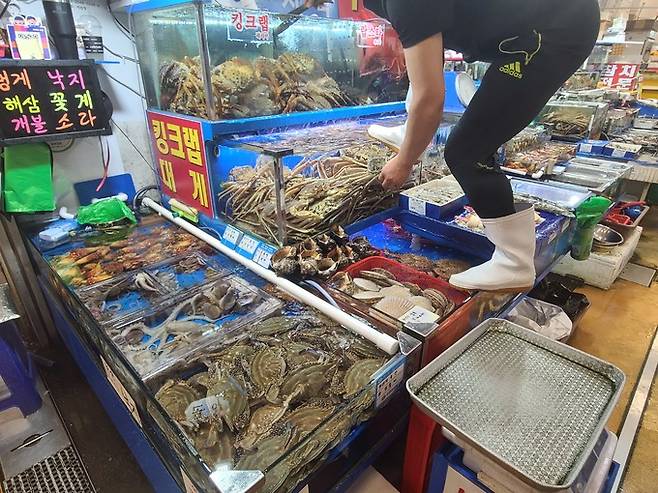 서울 동작구 노량진 수산시장에서 한 상인이 손님들의 가격 문의에 적극적으로 수산물을 보여주고 있다.