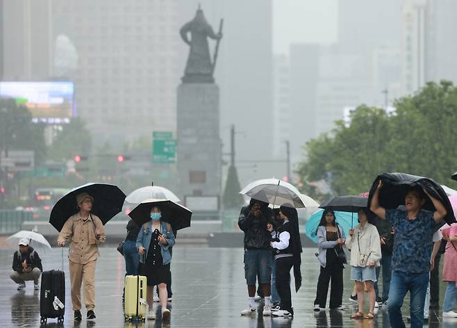 28일 서울 세종대로 광화문광장에서 우산을 쓴 관광객들이 오가고 있다. [연합]