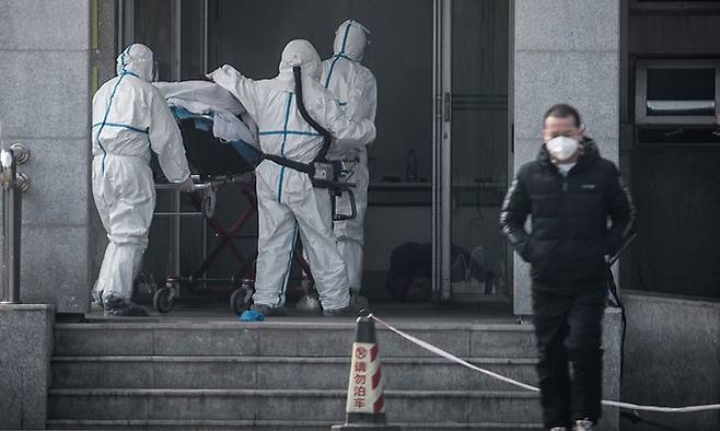 지난 2020년 1월 18일 코로나19가 발생한 중국 후베이성 우한에서 의료진이 폐렴 환자들을 집중 치료하고 있는 한 병원으로 환자를 옮기고 있다. AFP연합뉴스