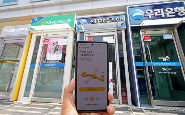 서울 시내의 시중은행 현금자동입출금기(ATM) 앞에서 지난달 31일 서비스를 시작한 대환대출 인프라가 스마트폰에 실행되고 있다. 연합뉴스