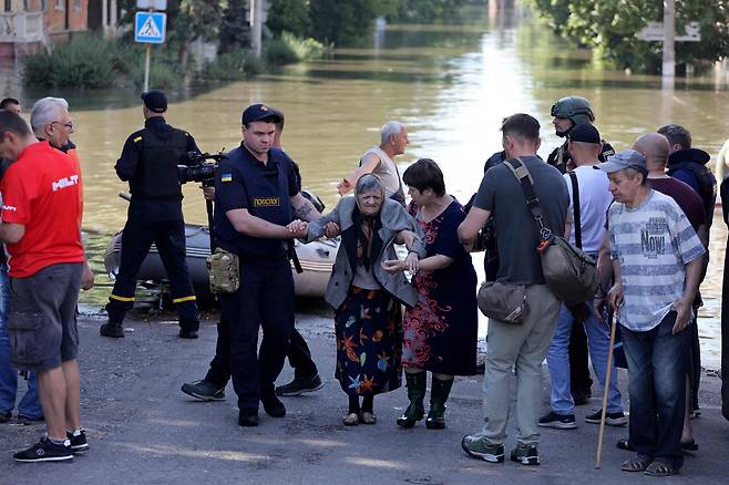 7일(현지시간) 우크라이나 헤르손의 홍수 지역에서 한 경찰관과 여성이 노인 여성의 대피를 돕고 있다. / 사진=AFP 연합뉴스
