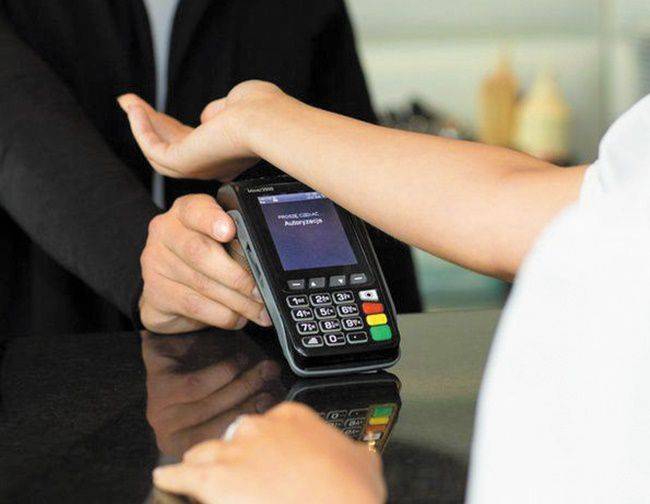 물건 값 계산을 위해 근거리 무선통신(NFC) 기술이 적용된 칩을 심은 손을 결제 단말기에 대는 모습. /BBC