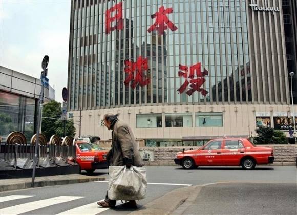 부동산 거품이 꺼진 1991년부터 2010년까지 이어진 경제 침체로 일본은 ‘잃어버린 20년’을 겪었다. 지난 2006년 6월 일본 열도가 가라앉는 재난 영화 ‘일본 침몰’ 홍보 문구가 걸린 건물 앞을 걸어가는 남성의 모습에서도 불황을 엿볼 수 있다. 도쿄 AP 연합뉴스