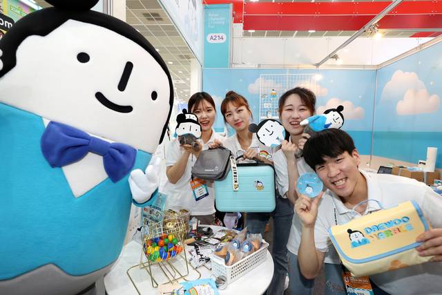 지난 13일 서울 강남구 코엑스 ‘2023년 캐릭터 라이선싱 페어’에 마련된 대우건설 캐릭터 ‘정대우’ 부스에서 대학생 홍보대사들이 직접 만든 굿즈를 들어 보이고 있다. 대우건설 제공