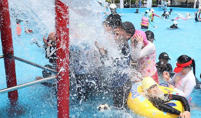 30일 오후 서울 성북구 성북초등학교 운동장에 마련된 물놀이장을 찾은 어린이들이 쏟아지는 물을 맞으며 더위를 식히고 있다. 김정효 기자