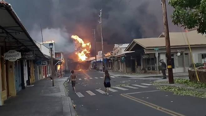 8일 거대한 산불이 발생한 하와이 마우이섬 중심가 라하이나의 한 거리에서 행인들이 산불을 바라보고 겁에 질려하고 있다. AP 연합뉴스