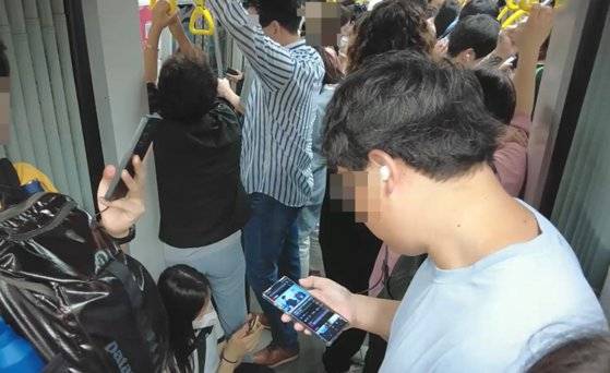 지난달 24일 출근시간 지하철 9호선 열차와 열차를 잇는 연결통로 바닥에 한 여성이 지친 모습으로 쭈그려 앉아 있다. 심석용 기자