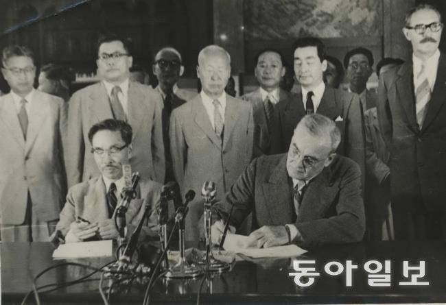 1953년 8월 8일 경무대에서 열린 한미상호방위조약 가조인식. 변영태 외무 장관과 존 포스터 덜레스 미 국무 장관(앞에 앉은 이들)이 서명하는 모습을 이승만 대통령(가운데)이 지켜보고 있다. 이승만대통령기념사업회
