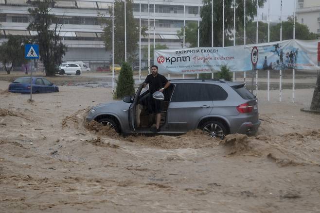 그리스 지역에 내린 폭우 속에서 한 남자가 차를 포기한 채 내리려 하고 있다. [EPA]