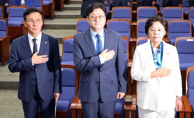 더불어민주당 원내대표 선거에 출마한 김민석(왼쪽), 홍익표(가운데), 남인순(오른쪽) 의원이 25일 투표 전 국민의례를 하고 있다. 연합뉴스