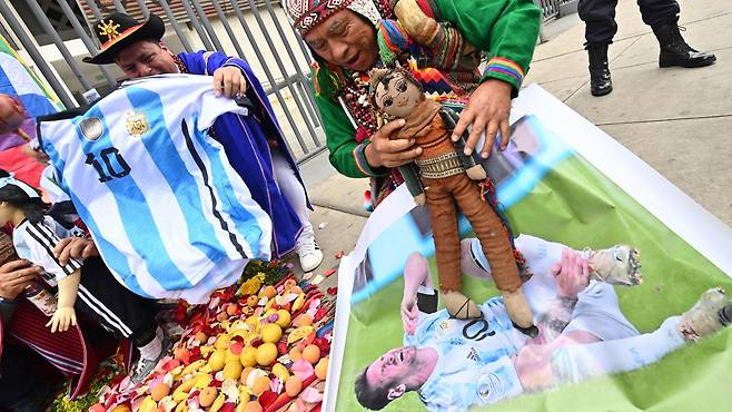 17일 페루 리마의 에스타디오 나시오날 데 리마 경기장앞에서 주술사들이 메시의 사진위에 인형을 올려놓고 주술을 걸고 있습니다./AFP 연합뉴스