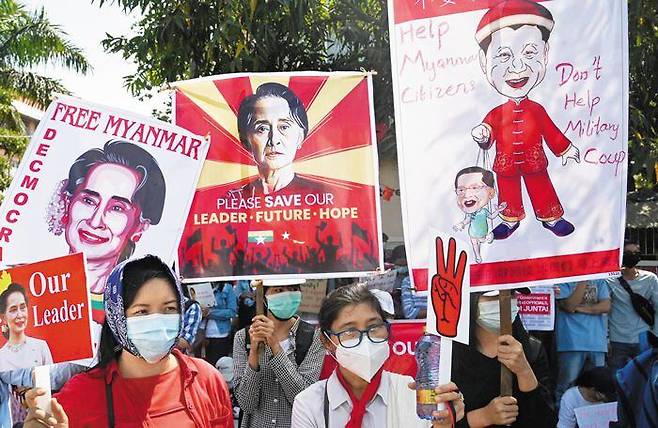2월 12일 미얀마 양곤의 중국대사관 앞에서 미얀마인들이 군부 쿠데타를 반대하는 시위를 벌이고 있다. 미얀마 군부는 2월 1일 쿠데타를 일으켜 아웅산 수지 국가고문 등 문민 정부 인사를 구금하고 권력을 장악했다. 일부 시위대는 아웅산 수지의 사진(왼쪽)을 들고 석방을 호소했고, 다른 시위대는 시진핑 중국 국가주석이 미얀마 군부를 조정하는 그림이 그려진 플래카드를 들고 있다. 중국이 쿠데타의 배후라는 취지다. /AFP 연합뉴스