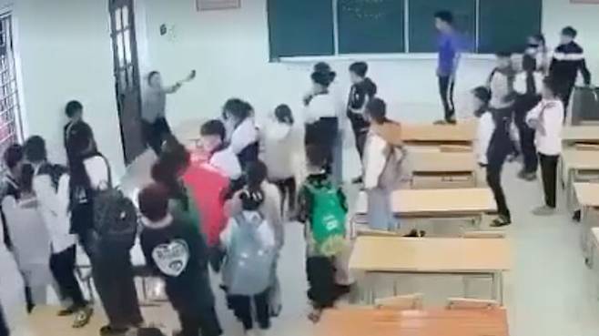 베트남의 한 중학교 교실에서 여러 학생들에게 둘러싸여 궁지에 몰린 여교사의 모습.