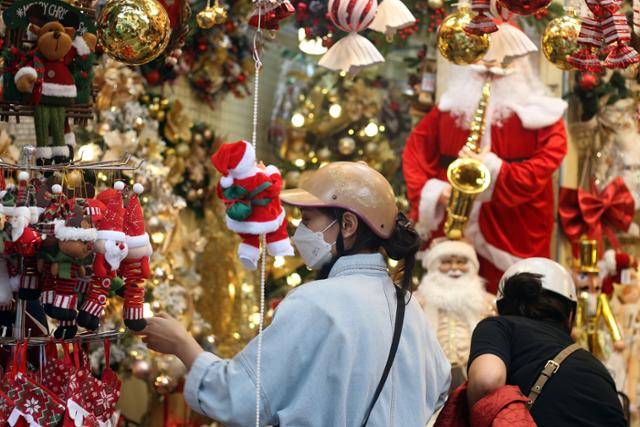 18일 베트남 하노이 항마거리에서 오토바이 헬멧을 쓴 한 여성이 크리스마스 장식품을 구경하고 있다. 하노이=허경주 특파원