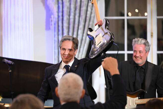 토니 블링컨 미국 국무장관이 지난달 27일 워싱턴DC의 국무부에서 열린 '글로벌 음악 외교 이니셔티브' 출범식에서 기타 연주를 하며 노래를 마친 뒤 기타를 들어 보이고 있다. /AFP 연합뉴스