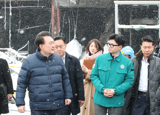 President Yoon Suk Yeol, left, and People Power Party interim leader Han Dong-hoon visit the site of a fire at a traditional market in Seocheon County, South Chungcheong, on Tuesday. Their meeting comes two days after the presidential chief of staff called on Han to step down as PPP chief. [JOINT PRESS CORPS]