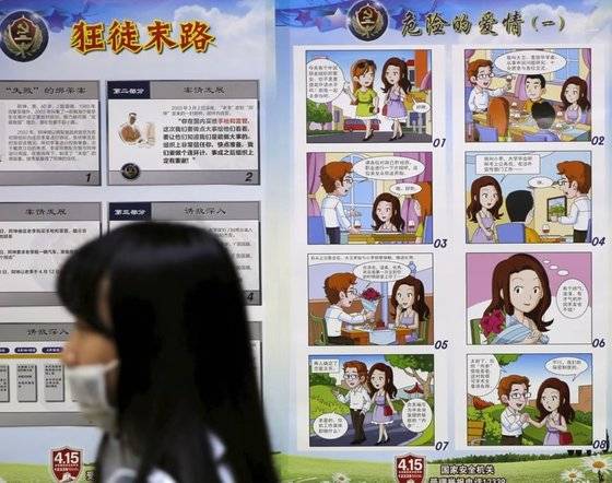 한 중국 시민이 지난 2016년 전국민 국가안보 교육의 날 제정을 맞아 불운한 여성이 외국인의 유혹에 넘어가 스파이가 될 수 있다고 경고하는 ‘위험한 사랑’ 만화 게시판 앞을 지나고 있다. FT 캡처