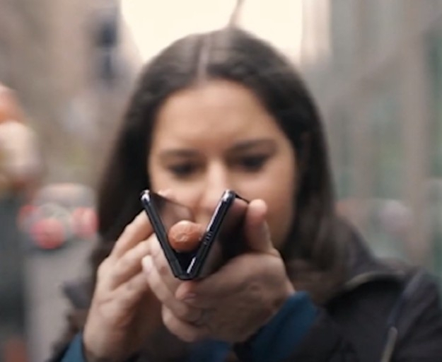 아이폰을 사용하는 미국 월스트리트저널(WSJ) 칼럼니스트가 삼성 폴더블폰에 소시지를 끼워 넣는 퍼포먼스를 하며 조롱하는 모습. (출처 : 유튜브 갈무리)