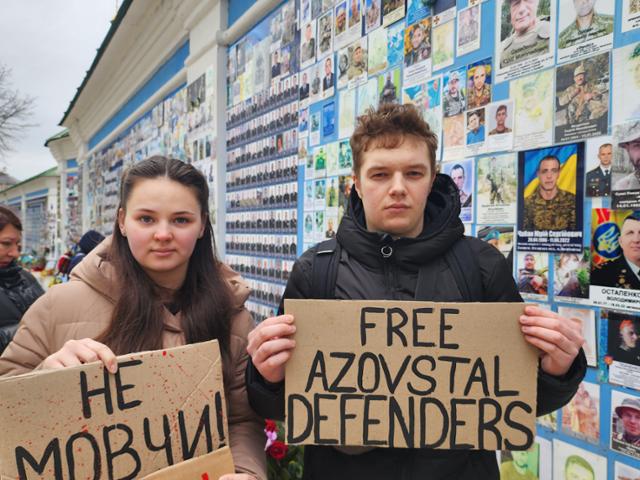 러시아의 우크라이나 침공 2년을 맞은 24일 우크라이나 수도 키이우 '추모의 벽' 앞에서 율리아(왼쪽)와 그의 남자친구가 러시아에 포로로 잡혀 있는 우크라이나 군인의 석방을 촉구하는 팻말을 들고 있다. 키이우=신은별 특파원