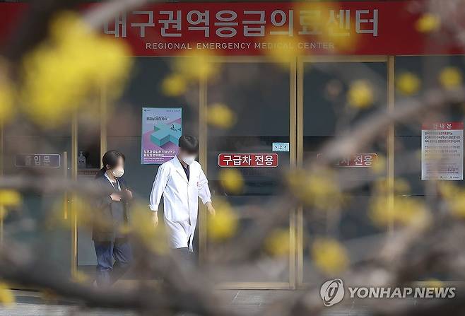 의료계 '춘래불사춘' (대구=연합뉴스) 윤관식 기자 = 전공의 집단이탈이 장기화하는 가운데 전국 의사 총궐기대회가 예정된 3일 대구 한 대학병원 응급실 앞에 개화한 산수유꽃 앞으로 의료진이 이동하고 있다. 2024.3.3 psik@yna.co.kr