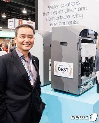 이상규 경동나비엔 북미법인장이 'AHR EXPO'에 전시한 수처리 시스템(Water Treatment System) 옆에서 기념사진을 찍고 있다.(경동나비엔 제공)
