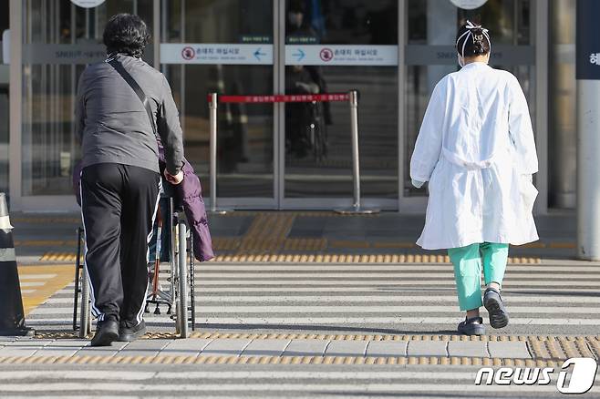 전공의들의 집단행동이 한 달째를 맞은 18일 서울의 한 대학병원에서 환자와 의료진이 나란히 길을 건너 병원으로 향하고 있다. 2024.3.18/뉴스1 ⓒ News1 민경석 기자