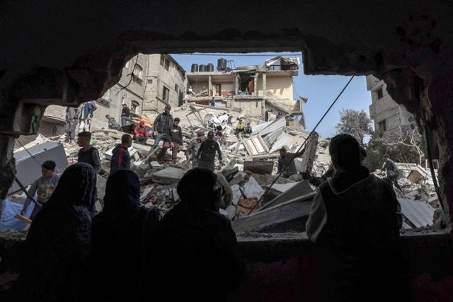 가자지구 최남단 도시 라파의 팔레스타인인들이 27일 밤새 이스라엘의 포격으로 파괴된 건물 잔해를 살펴보고 있다. 라파=AFP 연합뉴스
