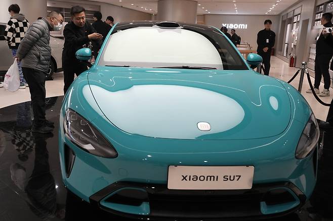 지난 26일 중국 베이징의 샤오미 자동차 플래그십 스토어에서 소비자들이 샤오미의 새 전기차 SU7을 살펴보고 있다. 베이징｜AP연합뉴스
