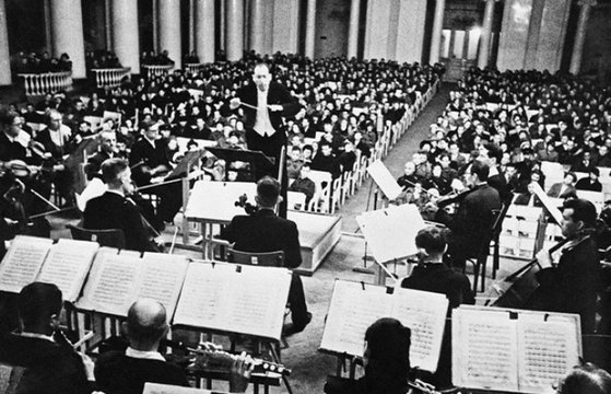 1942년 8월 9일 칼 엘리아스버그가 지휘하는 레닌그라드 라디오 교향악단의 쇼스타코비치 교향곡 7번 '레닌그라드' 초연 장면. 도시 곳곳에 스피커를 설치해 시민, 소련군은 물론 독일군까지 공연을 들을 수 있었다. Culture Matters