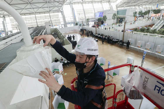 A worker covers a surveillance camera installed near an early voting site at Incheon International Airport on Thursday. Early voting for the April 10 general election will take place from 6 a.m. to 6 p.m. on Friday and Saturday across 3,565 polling stations nationwide. [JOINT PRESS CORPS]