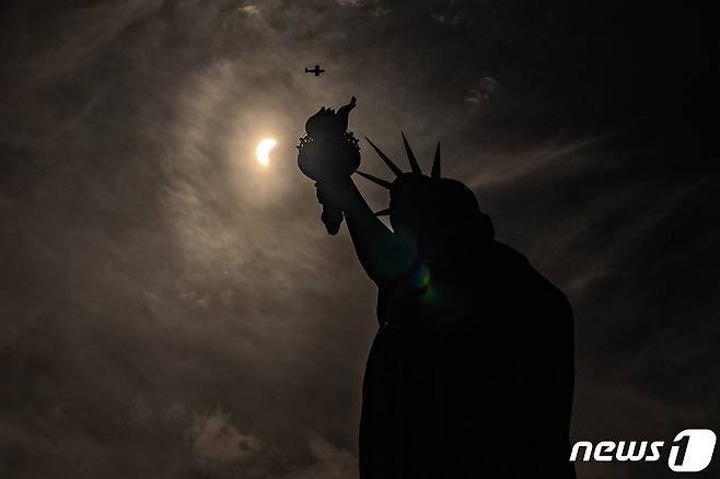 뉴욕 상공에서 자유여신상을 배경으로 일식이 진행되고 있다. ⓒ 로이터=뉴스1 ⓒ News1 박형기 기자