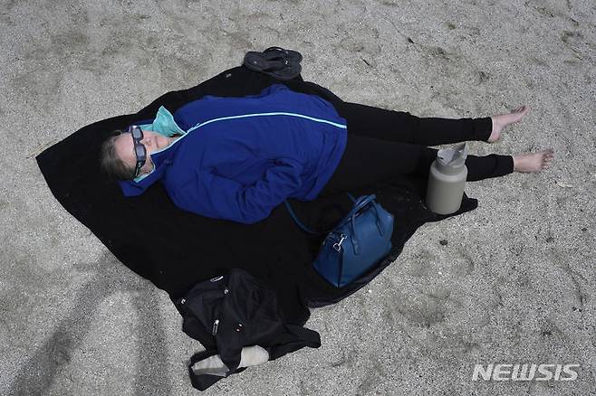 [루나피어=AP/뉴시스] 8일(현지시각) 미 미시간주 루나 피어에서 한 여성이 해변에 누워 달이 태양을 완전히 가리는 개기일식을 관측하고 있다. 2024.04.09.
