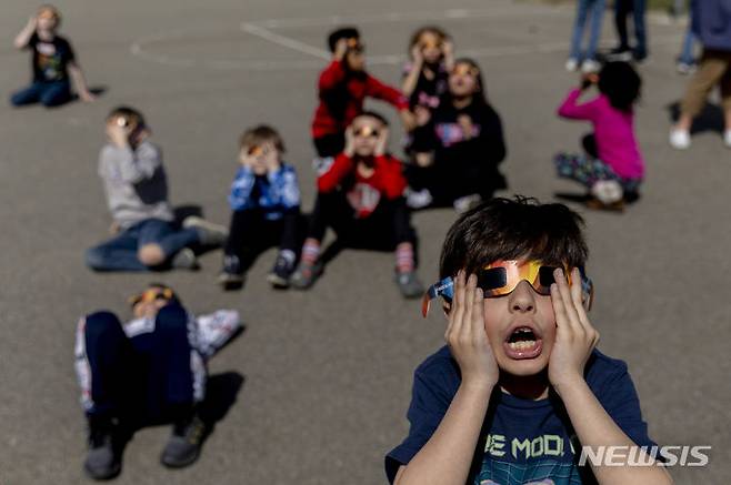 [미시간주=AP/뉴시스] 8일(현지시각) 미국 미시간주 그랜드블랑의 마이어스 초등학교에서 학생들이 개기일식을 관측하고 있다. 2024.04.09.