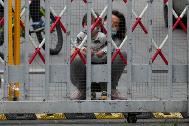 2022년 5월 코로나19로 봉쇄된 중국 상하이의 한 아파트 단지에서 한 여성이 아이를 안고 철문 밖을 바라보고 있다. 로이터연합뉴스